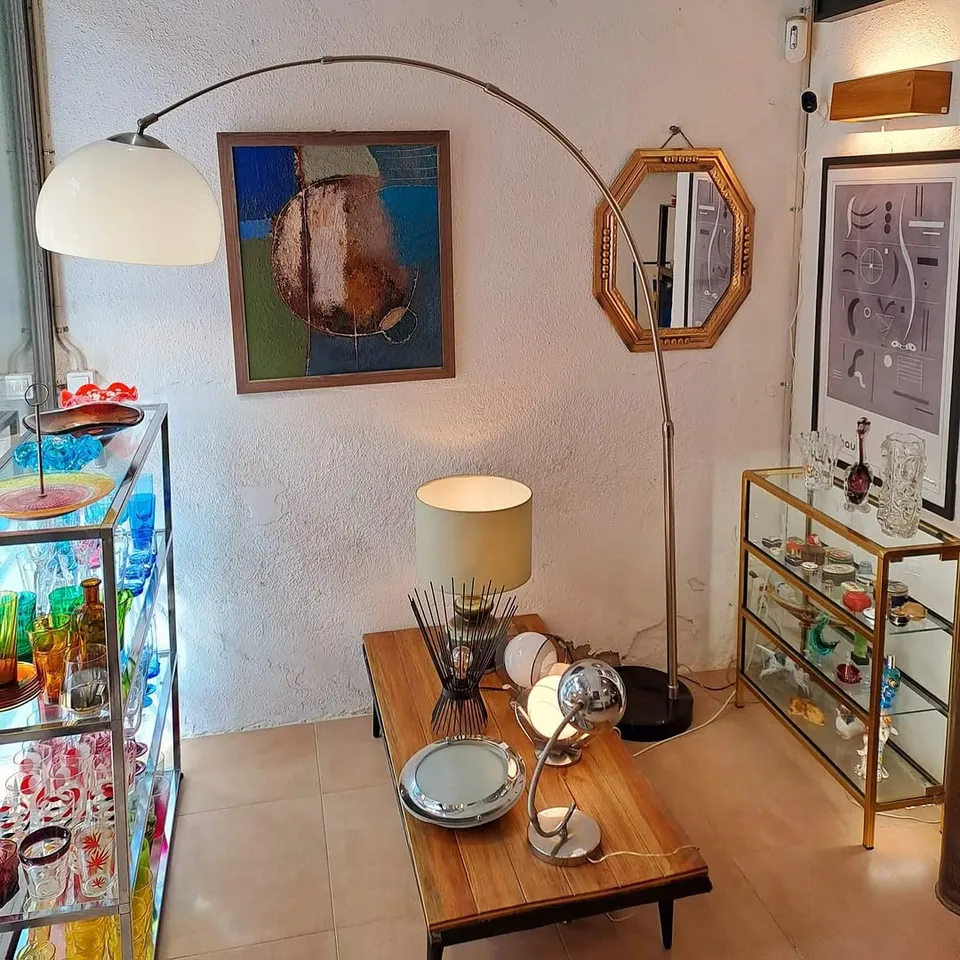 Racó de la botiga amb un llum d'arc, una vitrina de vidre de colors i quadres a la paret